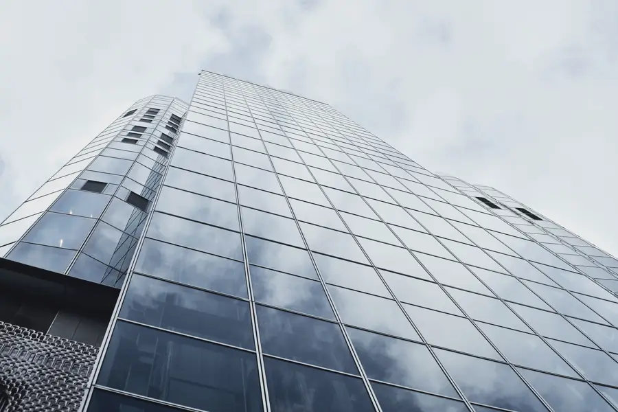 Glass office tower reflecting a cloudy sky