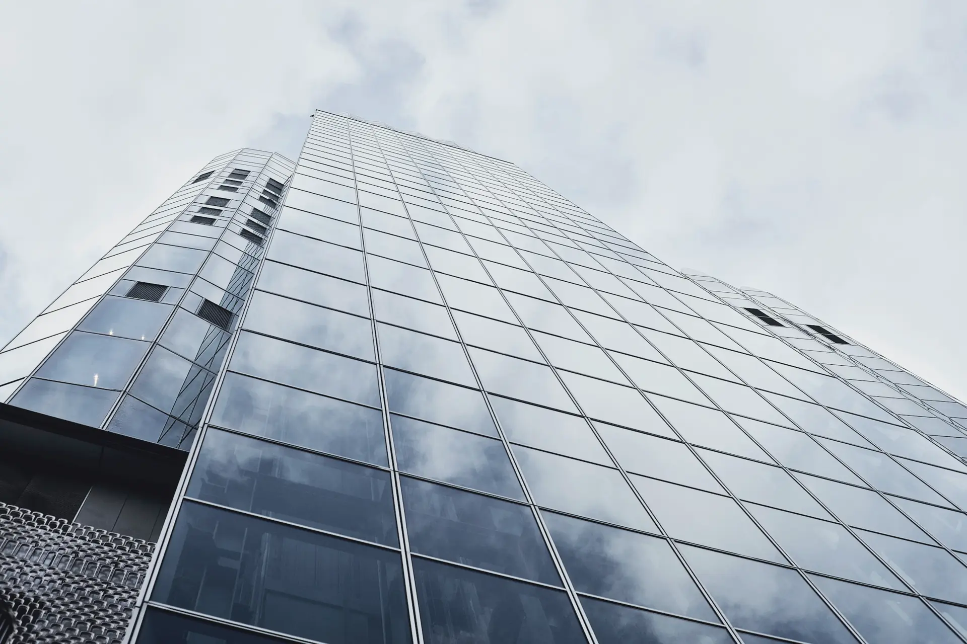 Glass office tower reflecting a cloudy sky