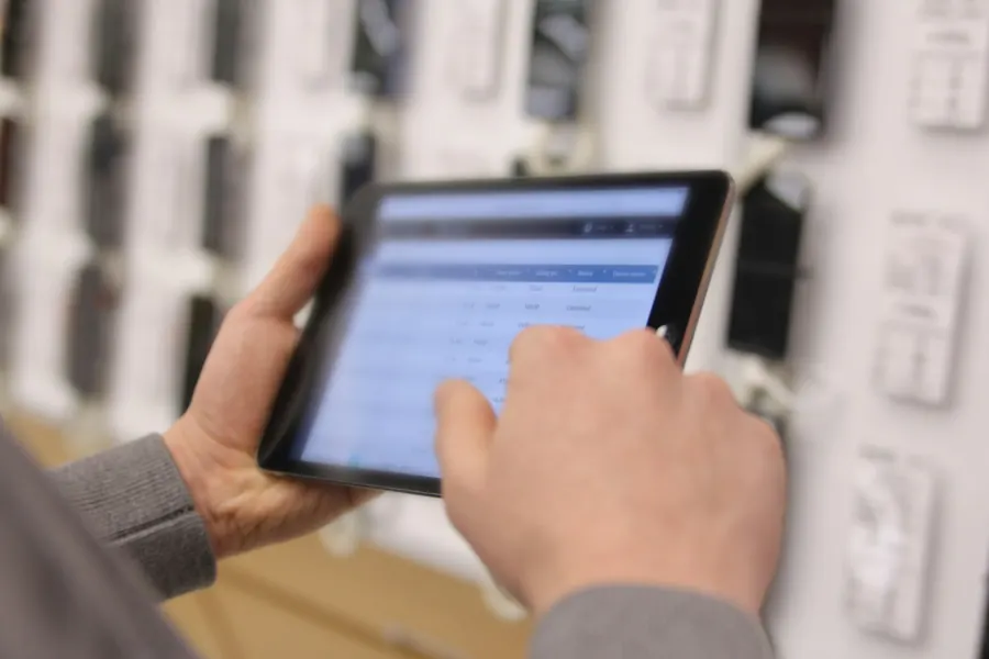 Hand using a tablet to review inventory and order records in a stockroom