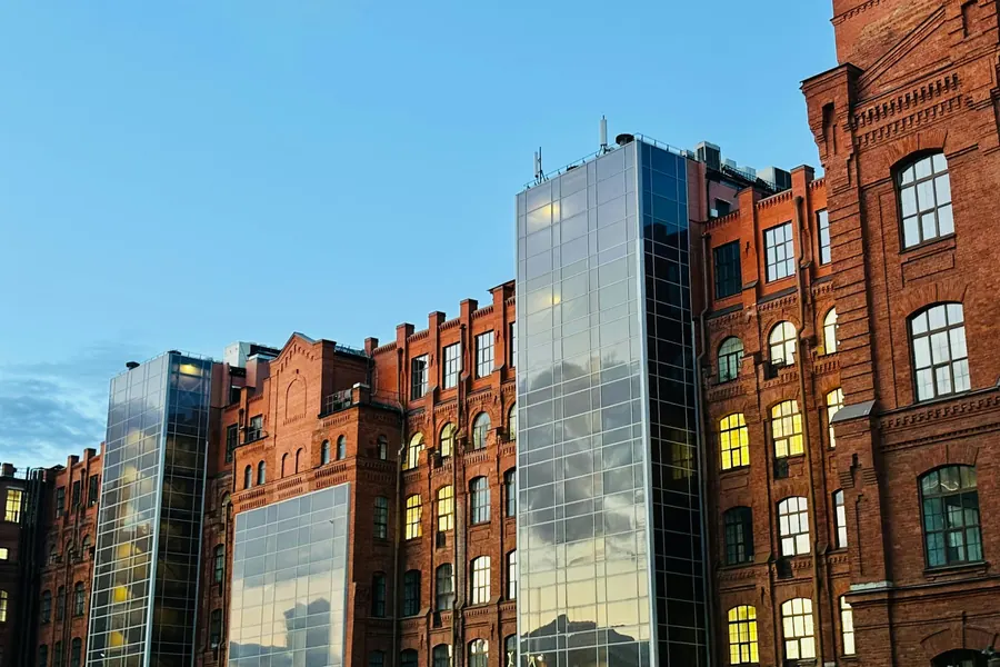Historic brick factory with modern glass towers built into its facade